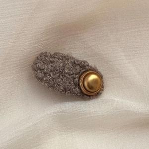 Close-up of vintage brown fleece hair clip with an elegant round golden metal button