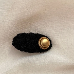Detail of elegant black lamb wool hair clip with a vintage matte gold metal button