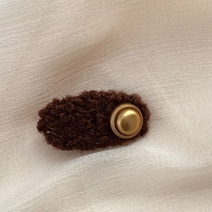Close-up of fluffy dark brown faux fur hair clip with vintage golden button detail