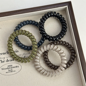 Minimalist spiral telephone cord hair ties in 5 vintage colors on a wooden tray