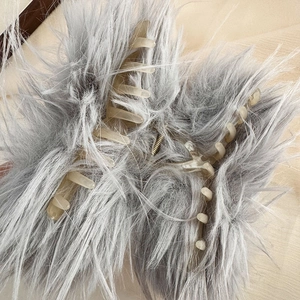 Dettaglio del fermaglio per capelli in finta pelliccia grigia con molla in metallo
