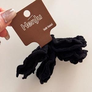 Close-up of ruffled black hair bands with high elasticity and branded display tag