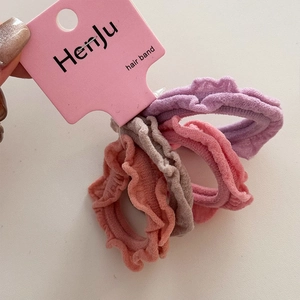 Detail view of four pleated elastic hair bands in soft purple, pink, and grey colors