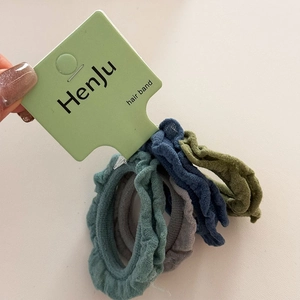 Detailed view of four multi-colored ruffled hair scrunchies on a retail display card