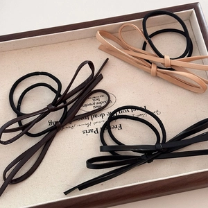 Élastiques à cheveux avec nœud en cuir minimalistes en noir, marron et beige sur plateau
