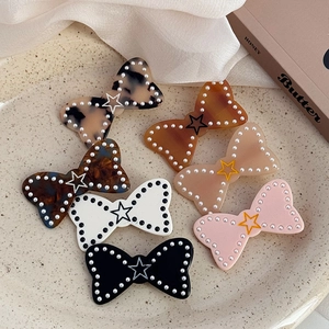 Détail de barrettes à cheveux noeud en acétate avec perles et motif étoile, coloris variés