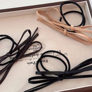 Élastiques à cheveux élégants avec nœud en cuir noir, marron et beige sur plateau à bijoux