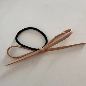 Détail d'un élastique à cheveux minimaliste avec nœud en cuir marron clair élégant