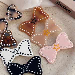 Set de barrettes noeuds en acétate avec perles et détail étoile sur plat en céramique