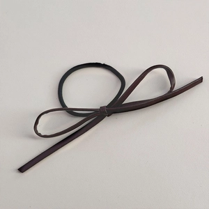 Détail de l'élastique à cheveux avec nœud en cuir marron et bande noire robuste