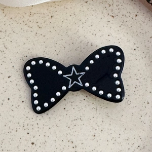 Barrette à cheveux nœud noir avec bords perlés argentés et détail étoile blanche