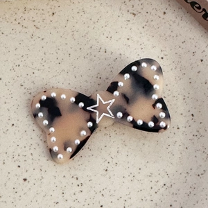 Détail d'une barrette nœud en écaille de tortue avec perles blanches et étoile