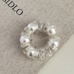 Gros plan sur élastique spirale transparent avec perles blanches sur tissu beige