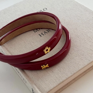 Détail d'un serre-tête en cuir verni rouge avec ornements dorés en forme de fleur et d'ours