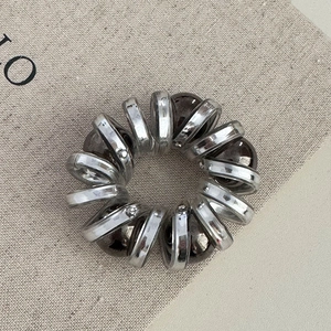 Vue détaillée d'un élastique spirale argenté avec perles brunes sur du lin