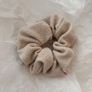 Détail d'un chouchou en maille côtelée beige montrant la texture douce et les plis