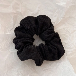 Vue détaillée du chouchou en tissu noir côtelé avec design plissé et élastique