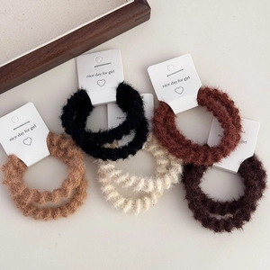 Detailed view of plush elastic hair ties in neutral tones with soft chenille texture