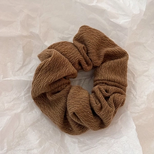 Détail d'un chouchou en maille marron foncé montrant une texture verticale et un tissu doux