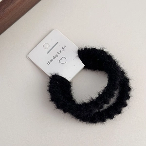 Detailed close-up of a black fuzzy hair tie on a white decorative display card