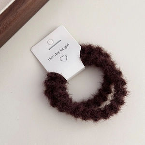 Close-up of soft brown plush hair scrunchie with cute branded display card packaging
