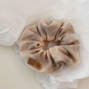 Detail of knitted hair scrunchie with smiley face patch and Hand Made leather label