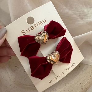 Dettaglio di fiocchi per capelli in velluto bordeaux con cuore dorato su cartoncino
