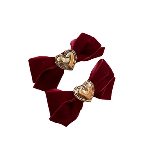 Paio di fermagli per capelli a fiocco in velluto rosso vino con fibbie a cuore dorate su bianco