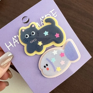 Mano che tiene una scheda con graziose mollette di peluche a forma di gatto e pesce