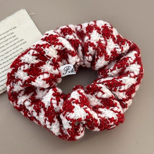 Detailed close-up of a festive red and white tweed knitted scrunchie with a logo label