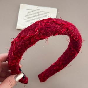 Close-up of red tweed headband featuring vintage frayed edges and woven texture details