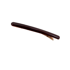 Pince à cheveux élégante en acétate caramel avec base en métal doré sur fond blanc