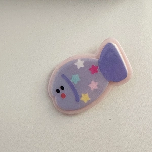 Dettaglio della molletta a forma di pesce viola con stelle colorate e morbida texture