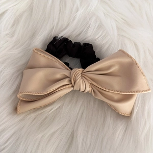 Détail d'un chouchou en similicuir rose avec élastique noir plissé sur tapis moelleux