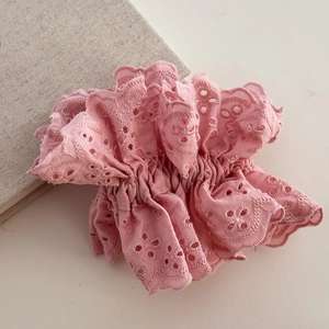 Close-up of pink lace scrunchie featuring delicate hollow embroidery and ruffled design