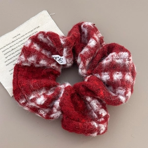 Detailed view of red and white knitted scrunchie texture with a small YM label detail