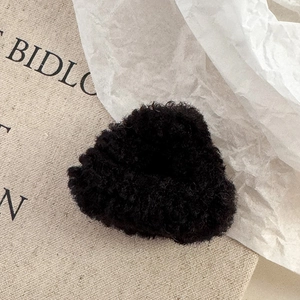 Gros plan sur la pince à cheveux noire en peluche avec texture douce en laine d'agneau
