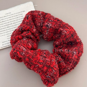 Detailed close-up of a red tweed scrunchie with metallic silver thread and elegant texture