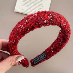 Close-up of red bouclé fabric headband with handmade label and silver glitter texture