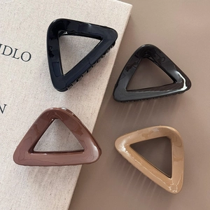 Glossy triangle claw clips in black, gray, coffee, and apricot on a neutral background