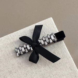 Détail d'une barrette en velours noir ornée de strass brillants et d'un nœud élégant