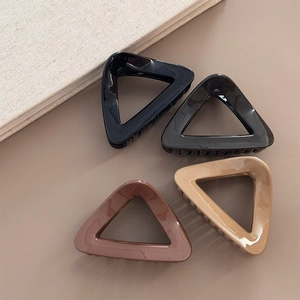 Minimalist triangular hair claw clips in neutral colors on a beige background