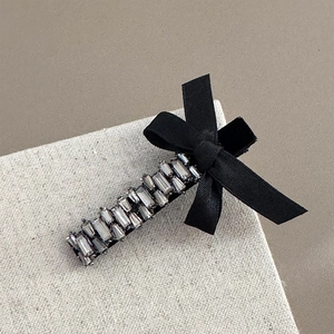 Détail du nœud en velours avec des strass gris luxueux sur une pince à cheveux