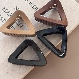 Close-up of minimalist triangular hair claws in beige, brown and black glossy finish