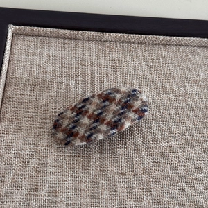 Détail d'une pince à cheveux ovale en tissu tweed à carreaux vintage pour l'automne-hiver