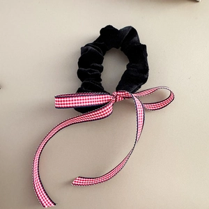 Detailansicht eines schwarzen Samt-Scrunchies mit einer rot-weiß karierten Schleife aus Band