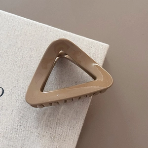 Detailed close-up of a glossy caramel triangular hair claw clip with strong metal spring