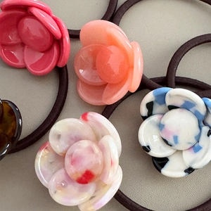 Macro view of multi-color acetate camellia flower charms on high-elastic hair ties