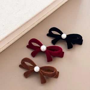Trois barrettes nœuds en velours noir, rouge et marron avec perles sur fond cuir beige