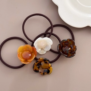 Detailed view of camellia resin charms on elastic hair ties in four elegant colors